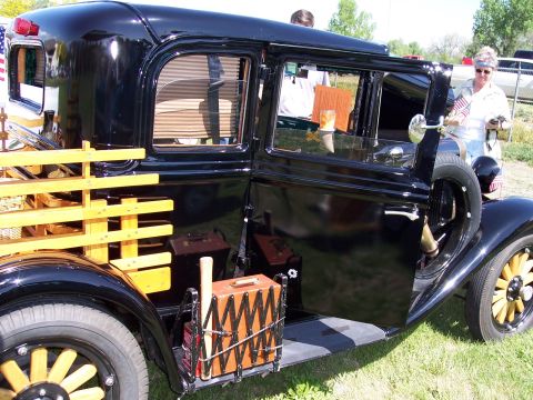 1972 Ford Ranchero - A vintage black pickup truck with a wooden bed is parked on grass, with its door open.