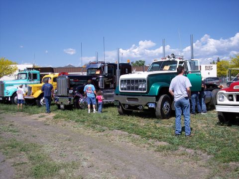 1972 Ford Ranchero - Several large trucks are parked in a grassy field under a blue sky with clouds.