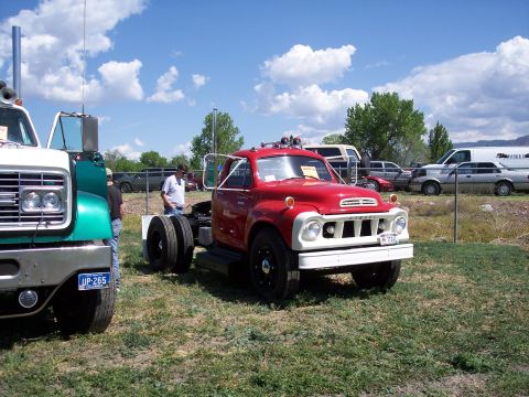 1972 Ford Ranchero - A red and white truck chassis with dual rear wheels is parked on grass at a car show, with other vehicles in the background.