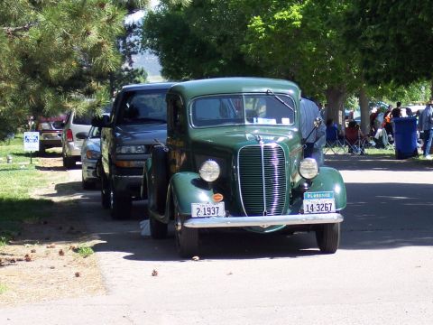 1972 Ford Ranchero - Green 1937 Ford pickup truck at a car show, with other vehicles and people in the background.