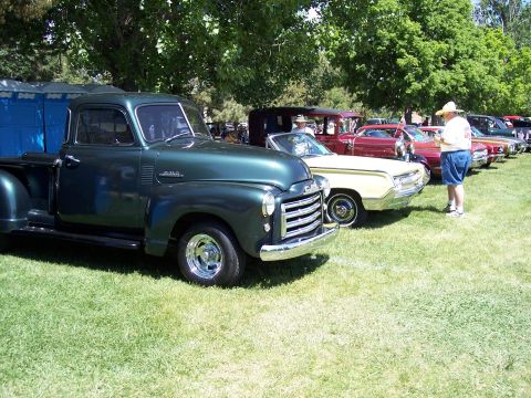 1972 Ford Ranchero - A line of classic cars are displayed on a grassy field under trees on a sunny day.