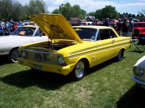 1972 Ford Ranchero - A yellow 1964 Ford Falcon is displayed with its hood open at an outdoor car show.