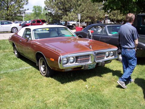 1972 Ford Ranchero - A brown and white 1973 Dodge Charger SE coupe is displayed at a car show, with other vehicles and trees in the background.
