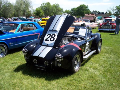 1972 Ford Ranchero - A black Shelby Cobra replica with racing stripes and the number 28 is displayed at an outdoor car show.