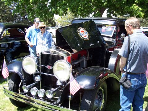 1972 Ford Ranchero - A black vintage car is displayed with its hood open, a circular emblem and American flags on the front.