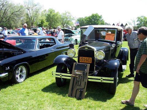 1972 Ford Ranchero - An antique black car is displayed with tools at a car show, with other vehicles in the background.