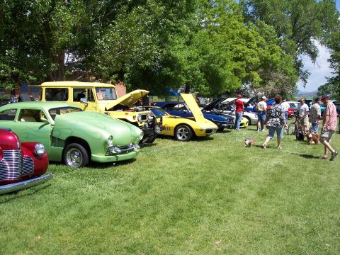 1972 Ford Ranchero - Cars and a truck are displayed on a grassy field under trees, with people mingling around.