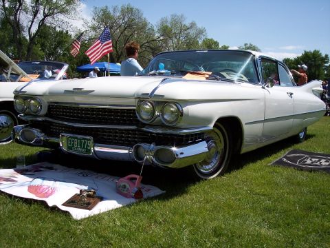 1972 Ford Ranchero - White 1959 Cadillac Eldorado on display at a car show with American flags in the background.