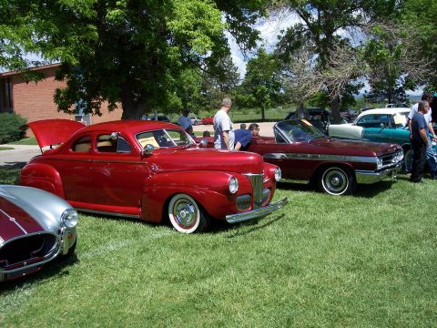 1972 Ford Ranchero - A red coupe from the 1940s is displayed at an outdoor car show with other vehicles.