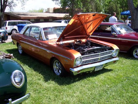1972 Ford Ranchero - A 1966 Ford Falcon in a metallic orange finish is displayed with its hood open at a car show.