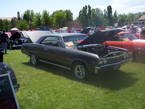 1972 Ford Ranchero - A dark gray 1967 Chevrolet Chevelle coupe is displayed with its hood open at an outdoor car show.