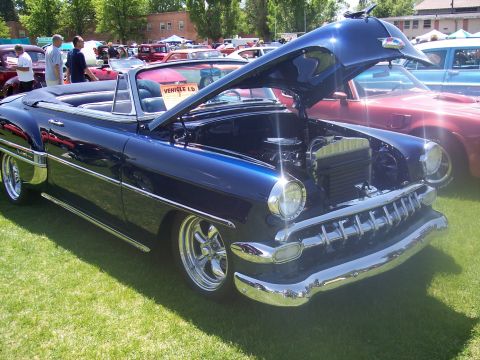 1972 Ford Ranchero - A blue convertible, likely a 1953 model, is displayed with its hood open at a car show, revealing the engine and chrome details.