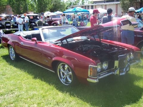 1972 Ford Ranchero - Red convertible at a car show, hood open, showing engine and chrome wheels.