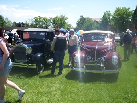 1972 Ford Ranchero - A maroon sedan is displayed at a car show, with a black vintage car to its left and other vehicles in the background.