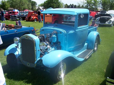 1972 Ford Ranchero - A bright blue pickup truck with its hood open is displayed at a car show, with other vehicles in the background.