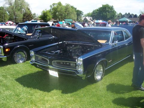 1972 Ford Ranchero - A dark blue 1967 Pontiac GTO is displayed with its hood open at a car show, alongside a black pickup truck.
