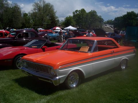 1972 Ford Ranchero - Orange and silver 1964 Ford Falcon coupe at a car show with other vehicles in the background.