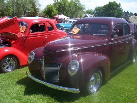 1972 Ford Ranchero - A maroon 1939-1940 Ford Coupe is displayed at an outdoor car show, with a red hot rod beside it.