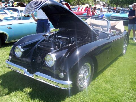 1972 Ford Ranchero - A black convertible with its hood open is displayed on a grassy field at a car show, with other vehicles visible in the background.