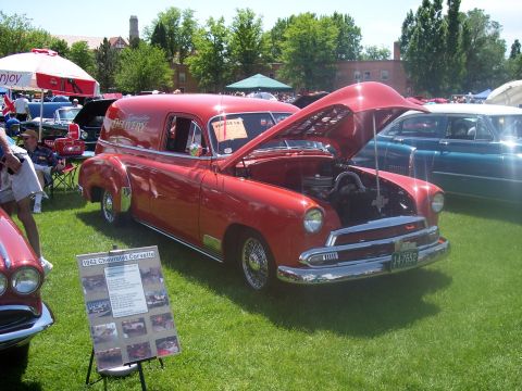 1972 Ford Ranchero - A red panel van is displayed at an outdoor car show with its hood open, parked on a grassy field.