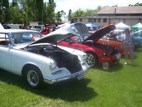 1972 Ford Ranchero - A white 1960s car is displayed with its hood open at a car show, alongside other vehicles.