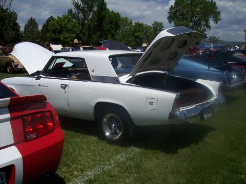 1972 Ford Ranchero - A white coupe with its trunk and hood open is displayed at an outdoor car show, with other vehicles visible in the background.