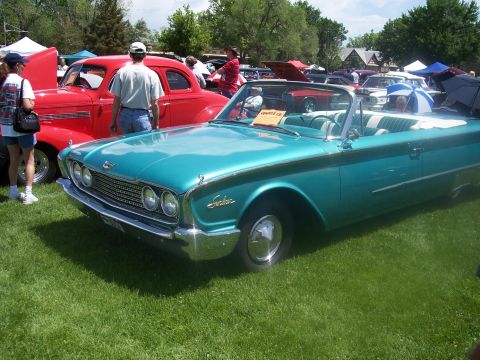 1972 Ford Ranchero - A teal convertible with a white interior is parked on the grass at a car show, with other vehicles and tents in the background.