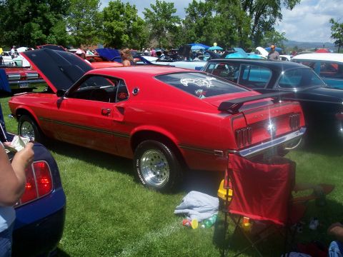 1972 Ford Ranchero - A red coupe with its hood open is displayed at an outdoor car show with other vehicles in the background.