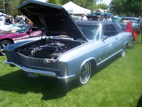 1972 Ford Ranchero - A classic 1965 Buick Riviera is displayed with its hood open at an outdoor car show.