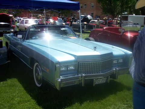 1972 Ford Ranchero - A light blue convertible is displayed at an outdoor car show with other vehicles and people in the background.