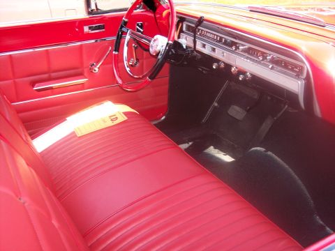 1972 Ford Ranchero - Interior view of a classic red car, possibly a 1965 Ford Falcon, with a yellow ID tag on the seat.