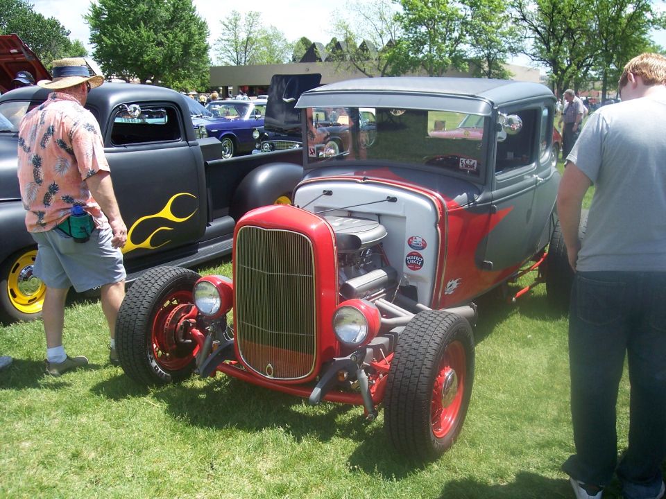 Red and gray hot rod coupe with exposed engine and flame decals on a black truck