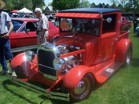1972 Ford Ranchero - A vintage red pickup truck with an open engine bay is displayed at an outdoor car show.