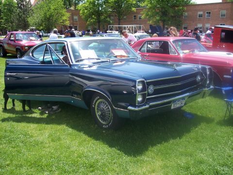 1972 Ford Ranchero - A dark blue 1967 AMC Rambler Rebel is displayed at an outdoor car show with other vehicles present.