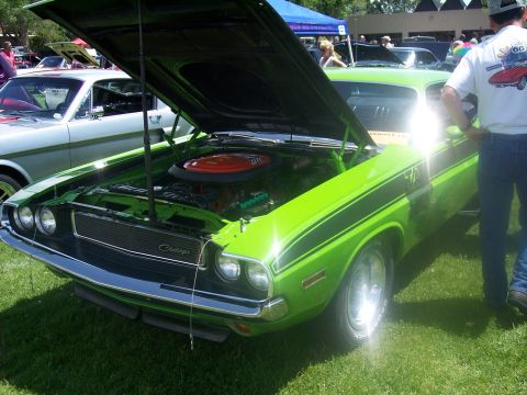 1972 Ford Ranchero - A lime green 1970 Dodge Challenger with black stripes is displayed with its hood open at a car show.