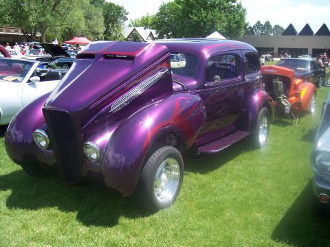 1972 Ford Ranchero - A customized purple hot rod sedan with flame graphics is displayed at an outdoor car show.
