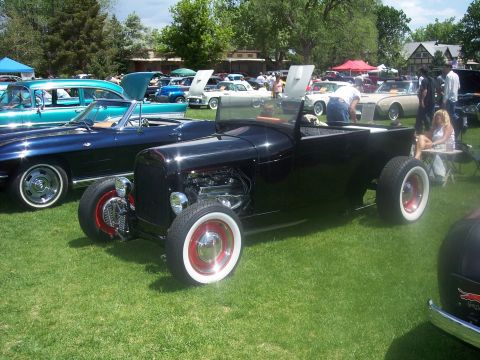 1972 Ford Ranchero - A black hot rod pickup truck is displayed at a car show with other vehicles in the background.