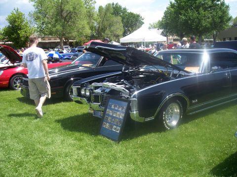 1972 Ford Ranchero - A display of classic cars at an outdoor event, with one car's hood open for viewing.