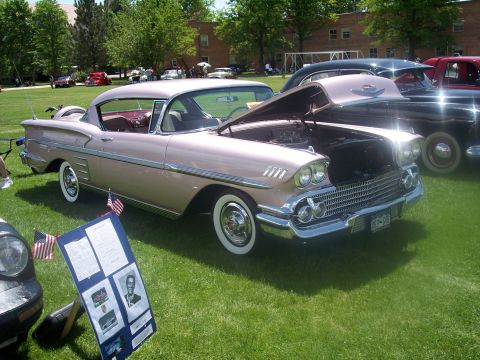 1972 Ford Ranchero - A pink 1958 Chevrolet Bel Air coupe is displayed with its hood open at an outdoor car show.