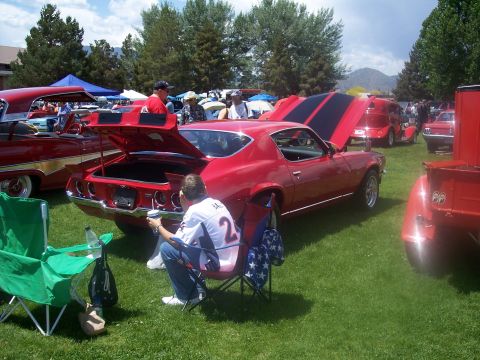 1972 Ford Ranchero - A red muscle car with black racing stripes is displayed at an outdoor car show.