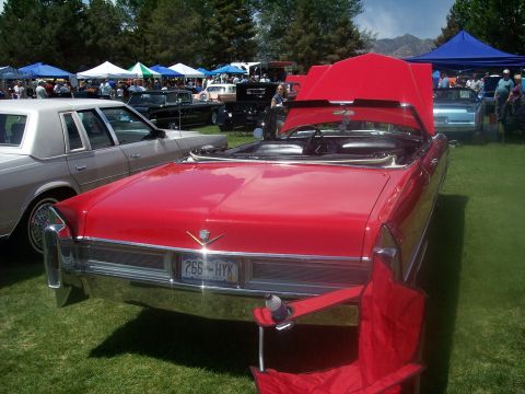 1972 Ford Ranchero - A red convertible Cadillac is parked on grass at a car show with other vehicles and tents in the background.