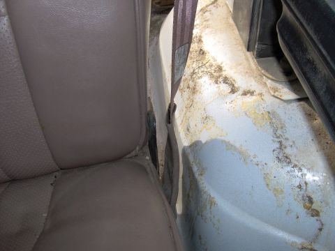 1993 Ford Bronco - Close-up of a vehicle's interior, focusing on the seat and the corroded door jamb area.