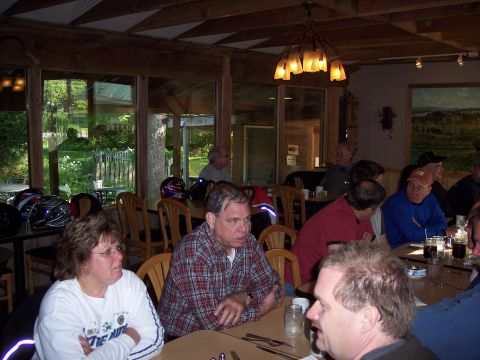 1985 Ford LTD Crown Victoria - A group of people are gathered inside a lodge, possibly after a motorcycle ride, with helmets visible on a table.