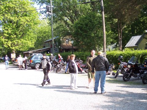 1985 Ford LTD Crown Victoria - A group of people and motorcycles gathered in a parking area on a sunny day.