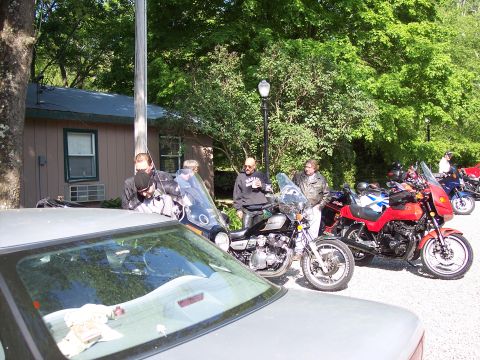 1985 Ford LTD Crown Victoria - A group of people gather around parked motorcycles on a sunny day.