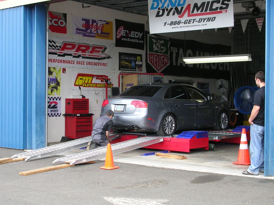 Silver Audi A4 sedan on a red Dyno Dynamics chassis dyno in a tuning shop