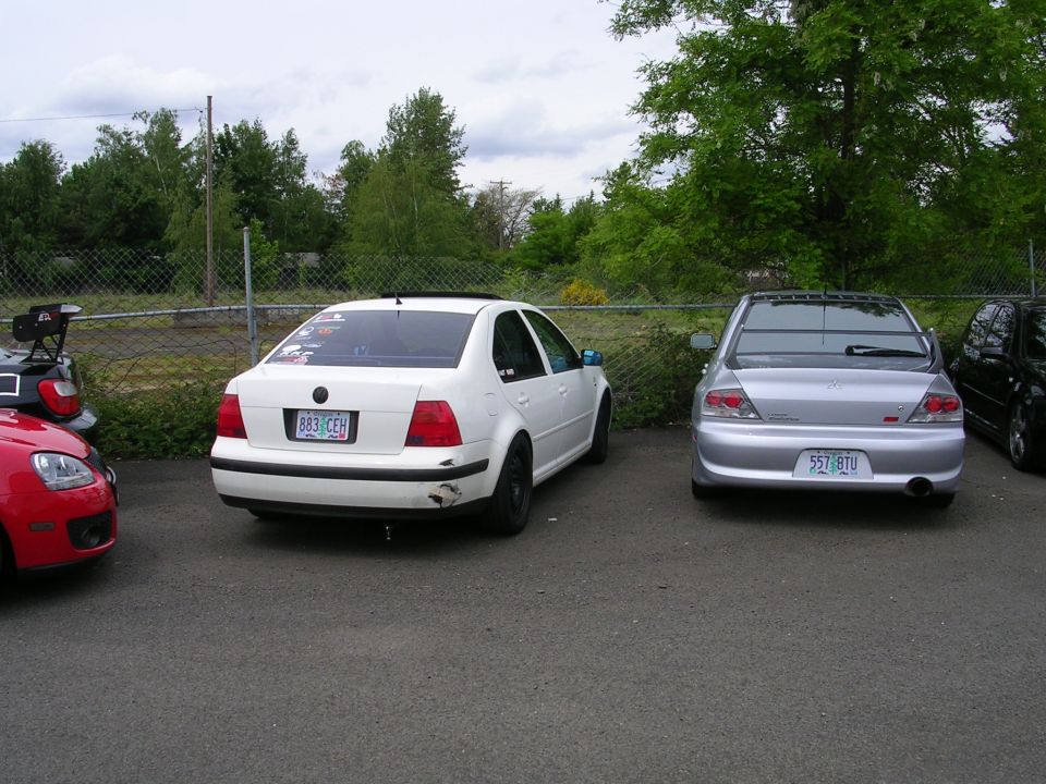 white sedan with a spoiler and a silver sedan parked outside