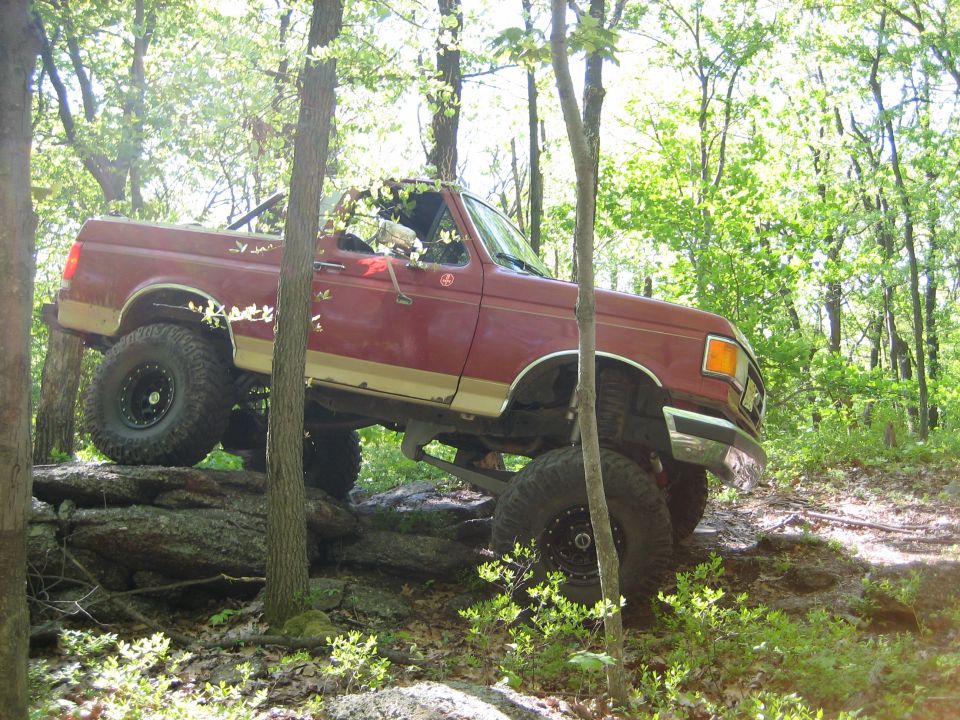 Red 1990 Ford Bronco navigating rocky terrain