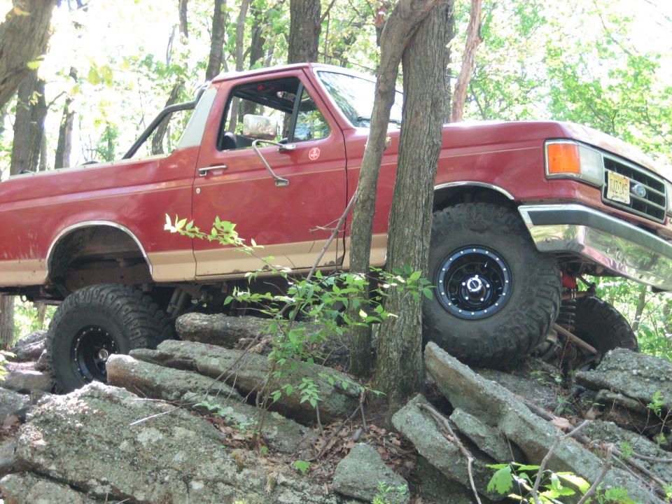 Red 1990 Ford Bronco on rocks