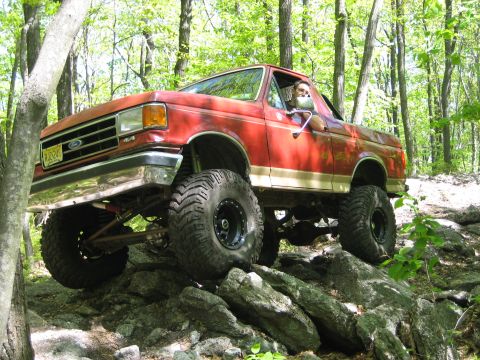 1990 Ford Bronco - This lifted 1990 Ford Bronco navigates a rocky trail in a wooded area.